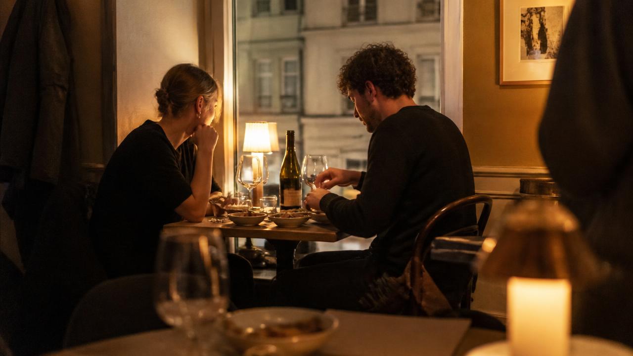 Två personer delar en flaska vin på en liten restaurang i Stockholm