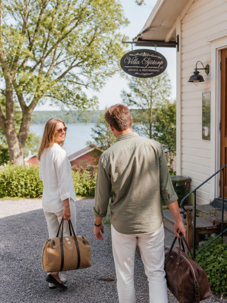 Två personer anländer med weekendbagar till ett litet hotell vid en sjö